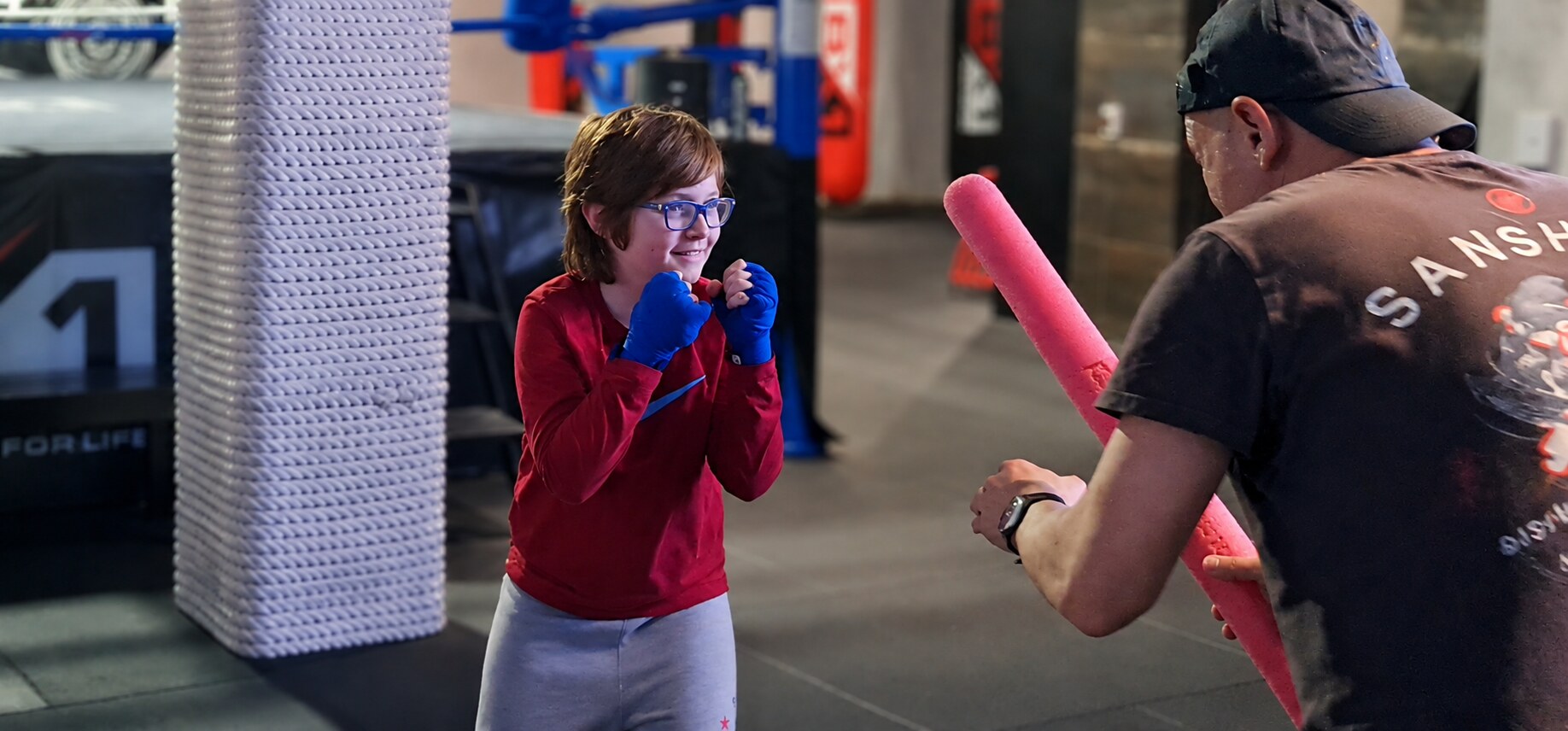 Child smiling during a supervised boxing reaction game with a BX1 coach at a school holiday program